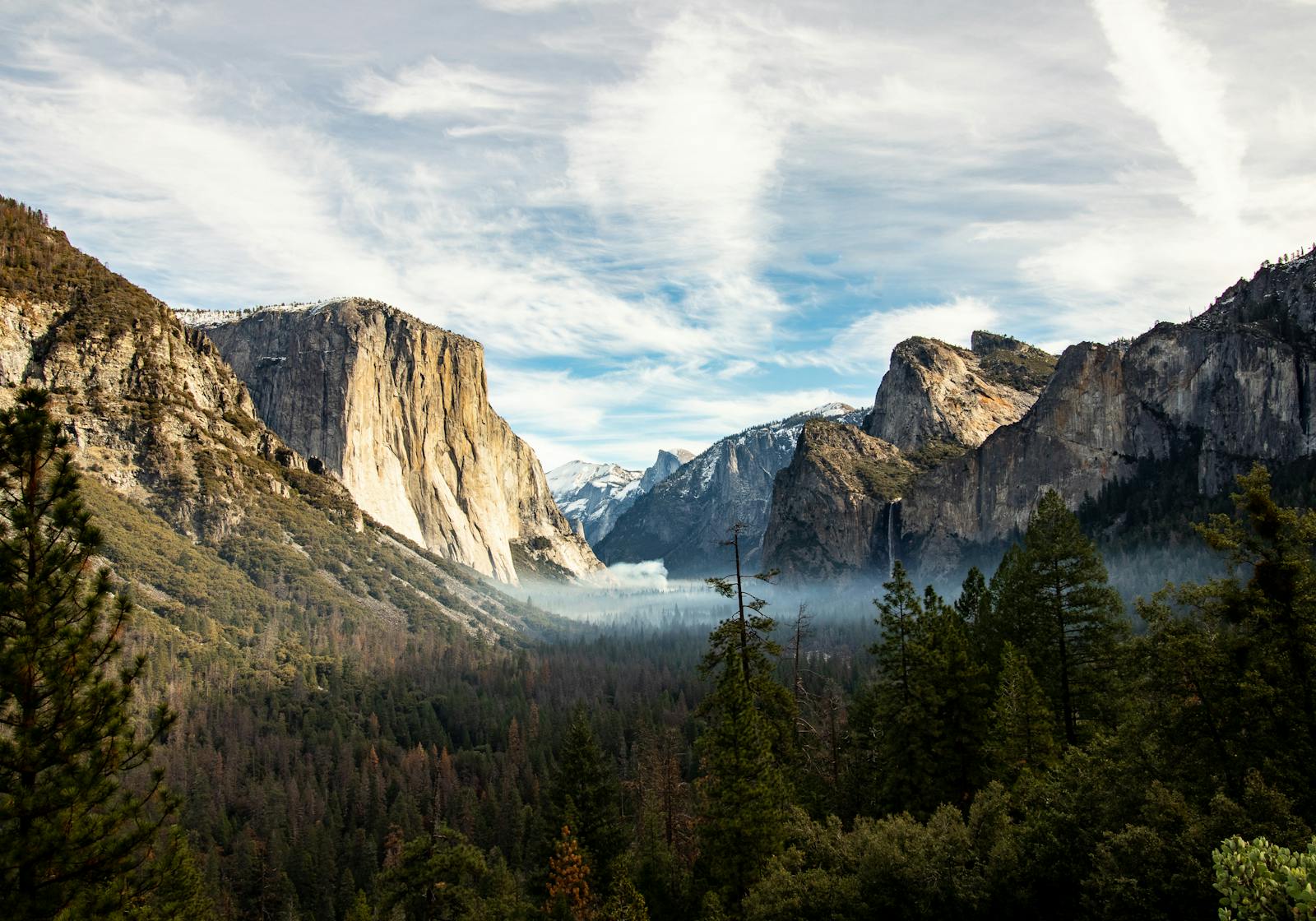 Majestic view of Yosemite Valley featuring El Capitan and surrounding mountains under a blue sky.