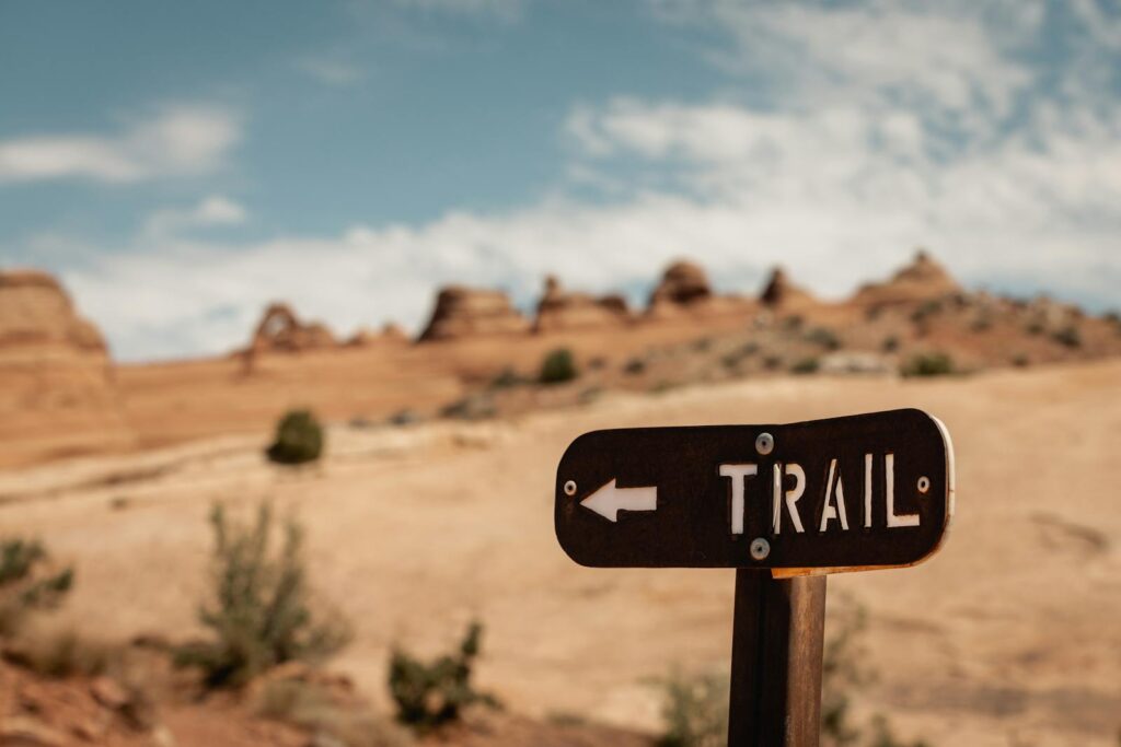 Trail sign against iconic rock formations in Utah's Arches National Park, USA.