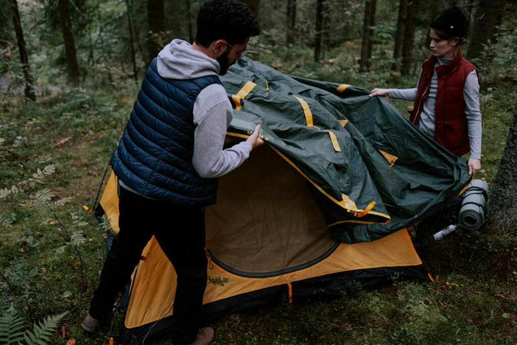 A couple setting up a tent in a forest, enjoying a camping trip.